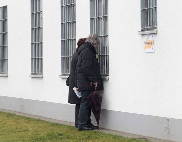 Zwei Personen schauen von außen in ein Fenster mit Gittern. (Bild: LWL/Cord)