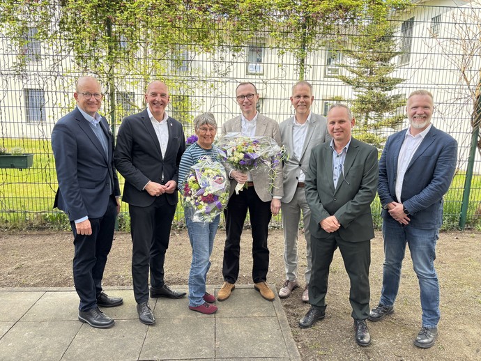 Eine Gruppe von Menschen steht in einem eingezäunten Innenhof (LWL-Bild: SchuFi)