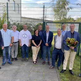 Eine Gruppe von Menschen steht in einem Innenhof, im Hintergrund eine Mauer (LWL-Bild: SchuFi)